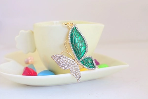Detalle de llavero de mariposa con esmalte verde y cristales brillantes para regalo.