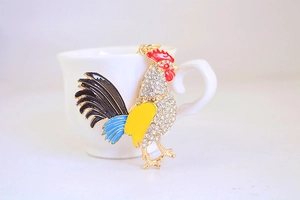 Vue détaillée du porte-clés coq doré orné de strass brillants sur une tasse en céramique