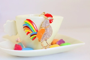 Détail d'un porte-clés coq coloré avec strass sur une tasse en céramique