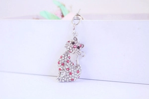 Gros plan d'un charme de chat assis avec des strass en cristal blanc et rose