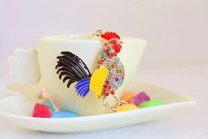 Vue détaillée d'un porte-clés coq coloré serti de strass sur une tasse en céramique