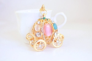 Close-up of golden pumpkin carriage keychain with pink opal and blue gemstones