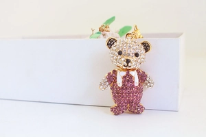 Detail of a luxury teddy bear keychain with white and purple rhinestones and enamel bow