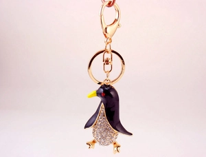 Close-up of cute black enamel penguin keychain with sparkling crystal belly and gold clasp