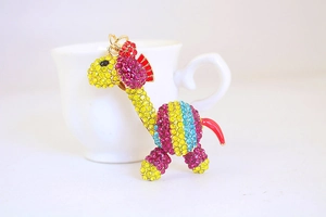 Dettaglio ravvicinato di un portachiavi a giraffa dorata con cristalli colorati su tazza bianca