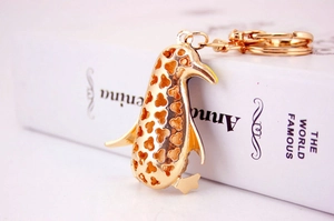 Detailed close-up of golden penguin charm with heart cut-outs on white book background