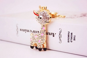 Macro detail of gold-plated giraffe keychain with sparkling rhinestones and pink enamel