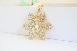 Détail d'un porte-clés flocon de neige doré avec perle et strass brillants arc-en-ciel