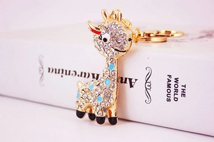 Detail view of gold giraffe keychain featuring white rhinestones and blue enamel dots