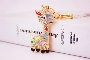 Detail of golden giraffe keychain with colorful rhinestones on a white book surface