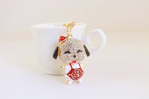 Detail of a gold dog keychain featuring white rhinestones and lucky red enamel charm