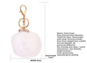 Detail of white faux fur pompom keychain with crystal crown and gold lobster clasp