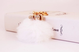 Detailed macro view of white fur pompom keychain with crystal crown gold ornament
