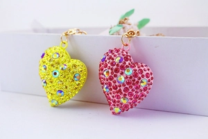 Dettaglio di portachiavi a forma di cuore con strass gialli e rosa e anelli dorati