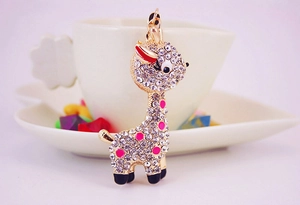 Detailed view of a sparkling rhinestone giraffe keychain hanging on a white coffee cup edge