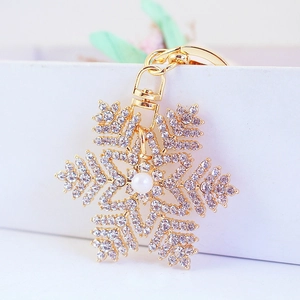 Porte-clés flocon de neige doré orné de strass brillants et d'une perle d'imitation
