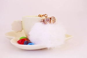 Detail of a white fluffy pompom keychain with a sparkling rhinestone gold crown on top