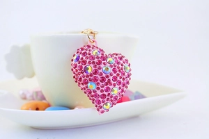Dettaglio del portachiavi a cuore con strass rosa appeso a una tazza bianca