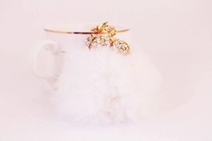 Detail of white faux fur keychain with gold lobster clasp and rhinestone encrusted accents