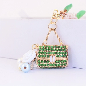 Porte-clés sac camélia exquis avec strass verts et perles blanches sur base dorée