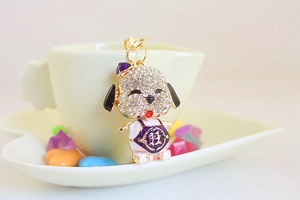 Close-up of alloy dog keychain with white rhinestones and a gold lucky character