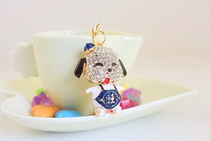 Detail view of a cute cartoon puppy keychain with rhinestones and a blue hat on a cup