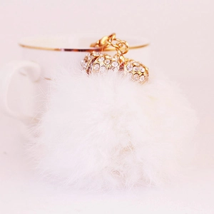 Cute white pompom keychain with golden rhinestone alloy chain on a pink background