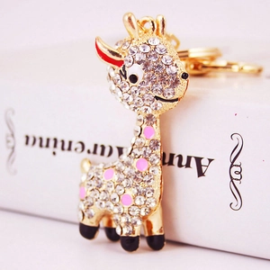 Golden giraffe keychain with sparkling white rhinestones and pink enamel dots on book