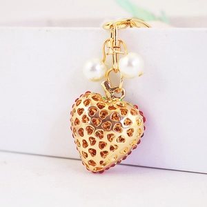 Cute heart-shaped keychain in gold metal with red accents and white faux pearls