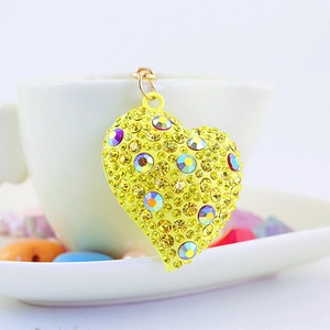 Portachiavi a cuore giallo scintillante con strass appeso a una tazza di porcellana bianca