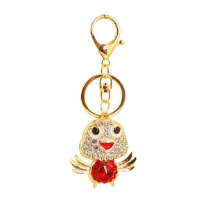 Close-up of golden bird keychain featuring red crystal gem and sparkling rhinestones