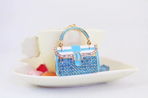 Detailansicht der Handtaschen-Schlüsselanhänger mit blauen Steinen an einer Tasse