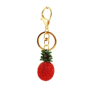 Detail of red rhinestone pineapple keychain with golden lobster clasp and green enamel leaf