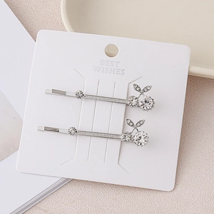 Close-up of sparkling crystal cherry hair clips with silver alloy base on white card