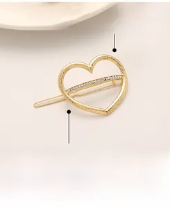 Detailed view of a gold hollow heart hair clip with sparkling white rhinestones inlay