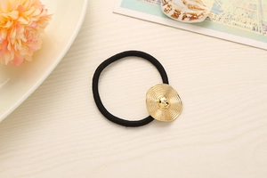 Close-up of black elastic hair band with a golden textured circular alloy ornament