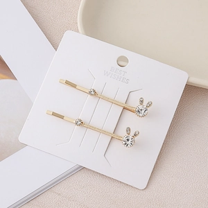 Detail of two-piece gold rabbit ear hair clips with crystals on a display card