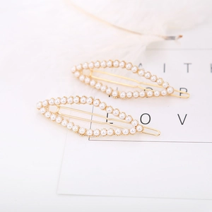 Detailed view of elegant gold hair clips with white pearls and spring clip design