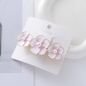 Fermaglio per capelli con fiori in smalto rosa e perle su cartoncino bianco