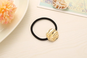 Detailed view of black elastic hair tie featuring a wavy gold metallic texture charm