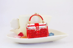 Detailaufnahme eines Mini-Handtaschen-Schlüsselanhängers mit roten Steinen und Goldgriff