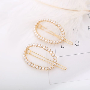 Elegant gold alloy oval hair clips with white pearls set against white feathers