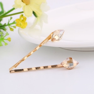 Close-up of golden hair pins with champagne crystal stones on a clean white background