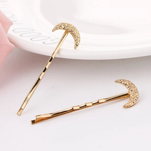 Elegant gold celestial moon hair clips with textured finish on a minimalist white tray