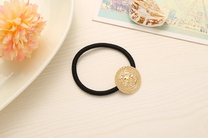 Detail of a black high-elastic hair tie featuring a golden lion head embossed alloy charm