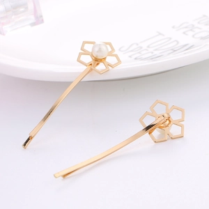 Barrettes dorées élégantes avec fleurs et perles blanches sur une assiette en céramique