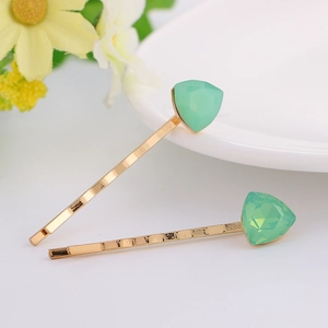 Detail view of two gold wave hairpins with green geometric crystal decorations