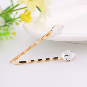 Macro view of gold alloy hair clips set with sparkling crystals on a white tray