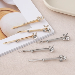 Close-up of crystal rabbit ear and cherry hair clips in gold and silver plating