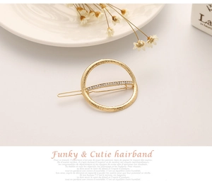 Close-up of golden round hair clip with hammered texture and sparkling rhinestones